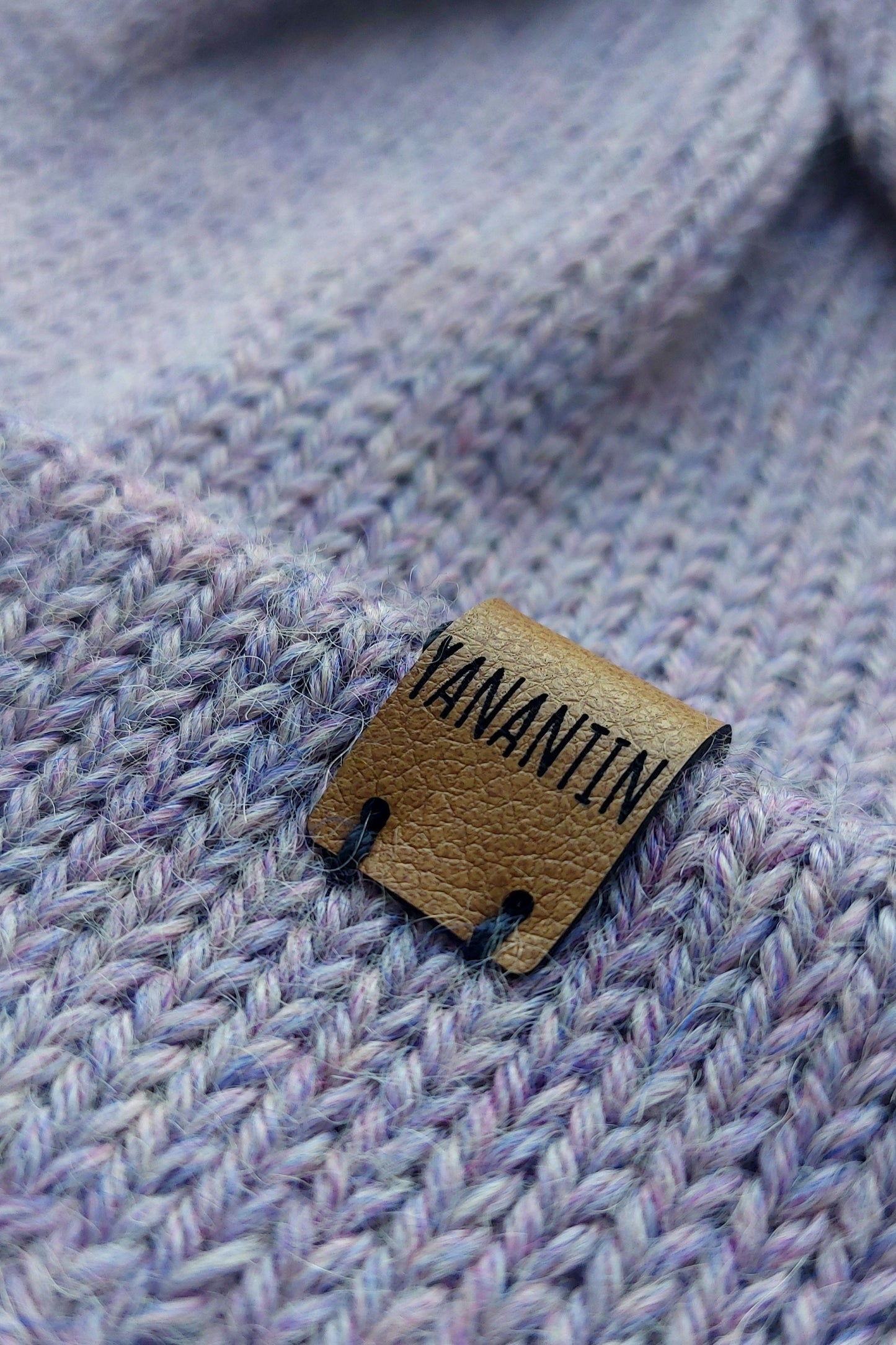 Close-up of the brown vegan leather label on the handmade lila baby hat, highlighting its quality and style.
