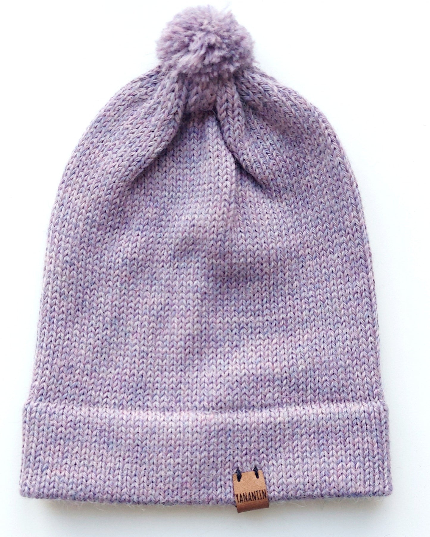 Handmade lila baby hat in soft 100% baby alpaca wool with a pompom, foldable edge, and brown vegan leather label, offering warmth and comfort.