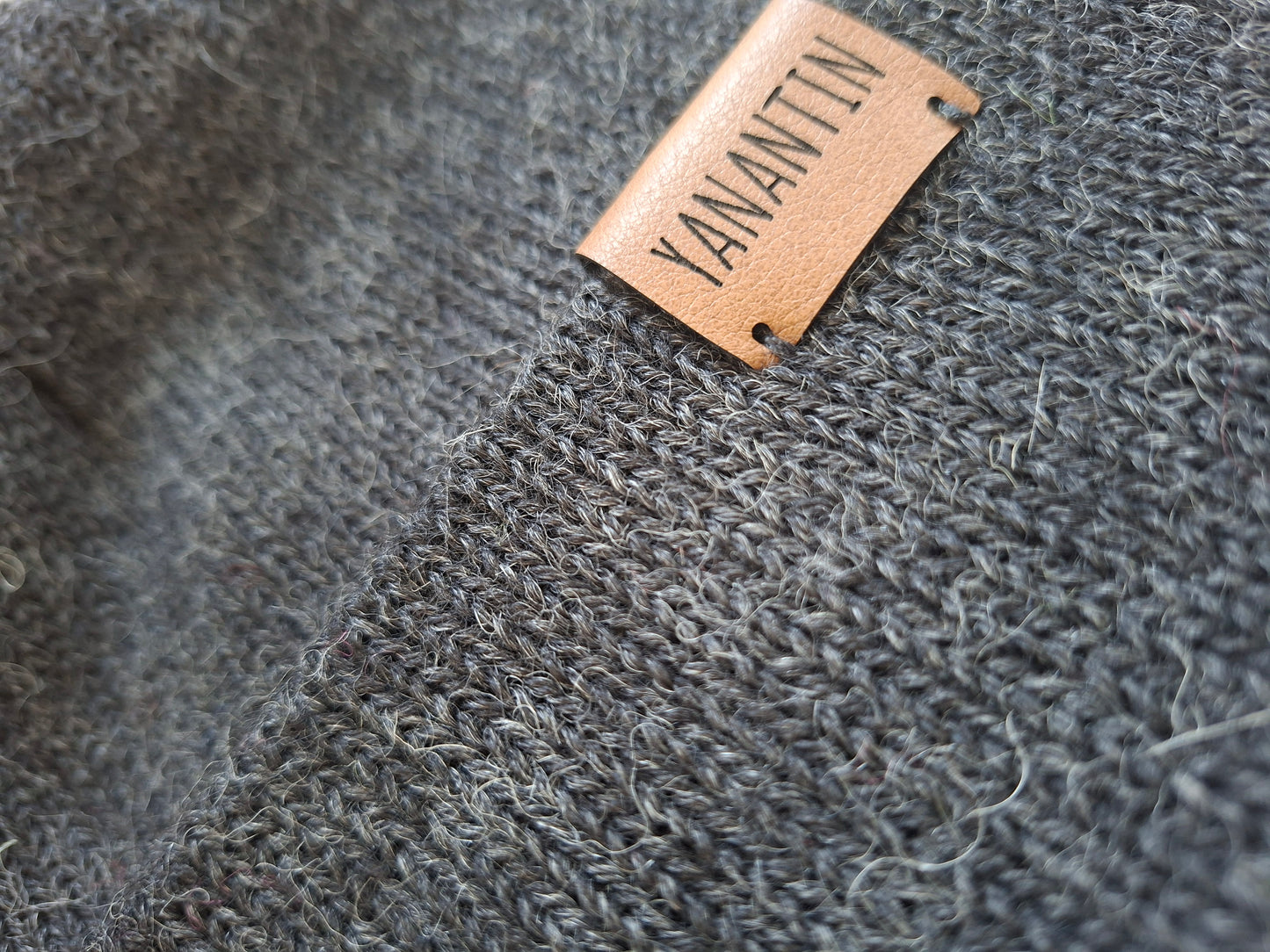 Close-up of a textured gray knitted woolen hat with a 'YANANTIN' label.