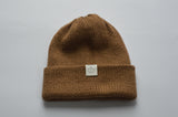 Camel brown knitted baby alpaca hat with a white organic cotton label and folded brim