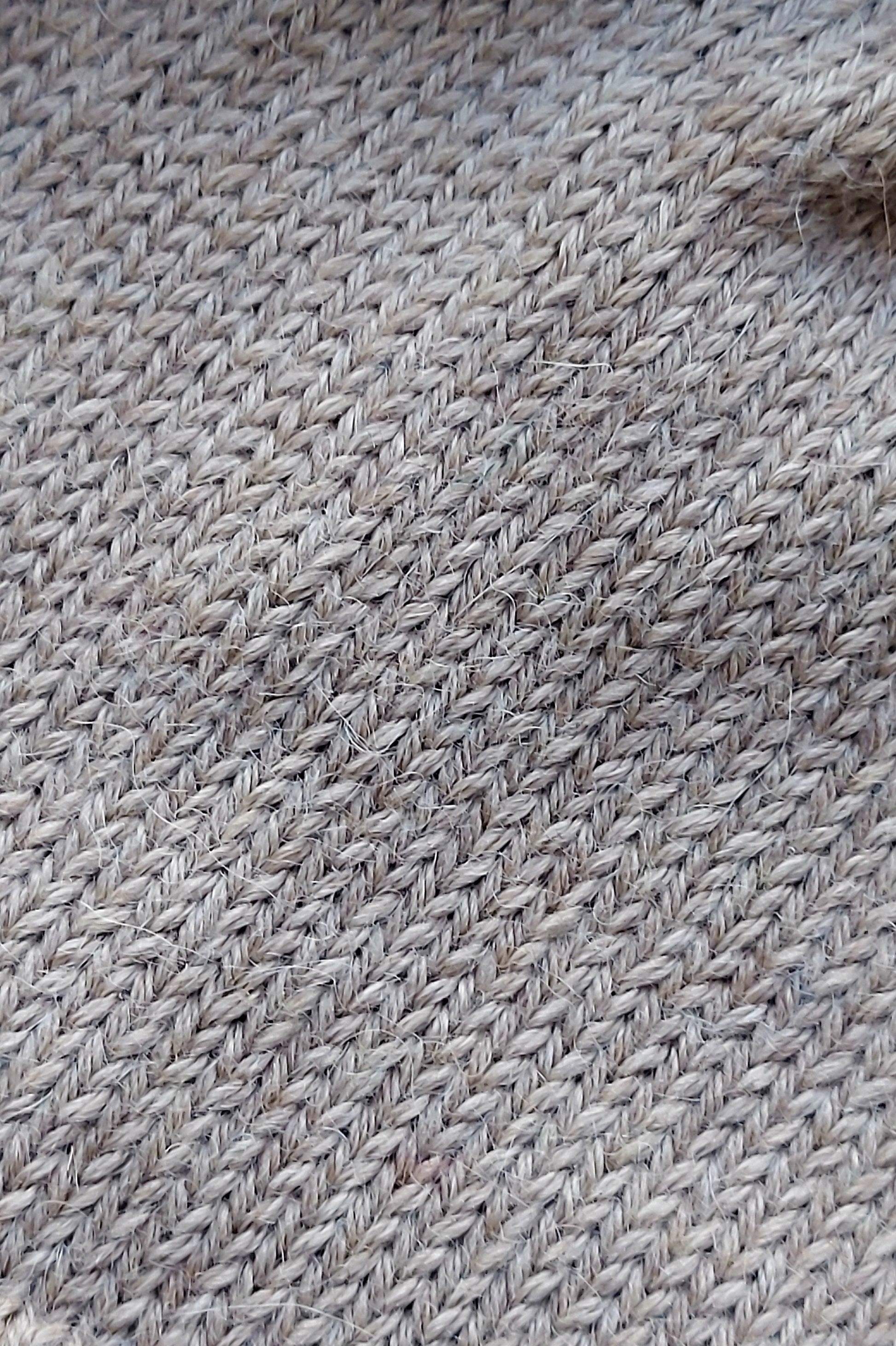 Close-up of the knitted texture of a light brown baby hat, made from 100% baby alpaca wool.