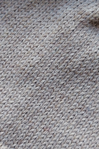 Close-up of the knitted texture of a light brown baby hat, made from 100% baby alpaca wool.