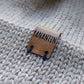 Close-up of the brown vegan leather label on a light brown knitted baby hat, made from 100% baby alpaca wool.