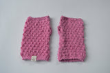 Pair of pink knitted fingerless mittens on a light background with an organic cotton label