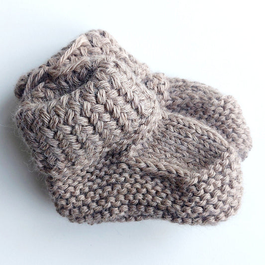 Handmade knitted baby socks in light brown with folded ankle cuffs, made from 100% baby alpaca wool—soft, stretchy, and perfect for little feet.