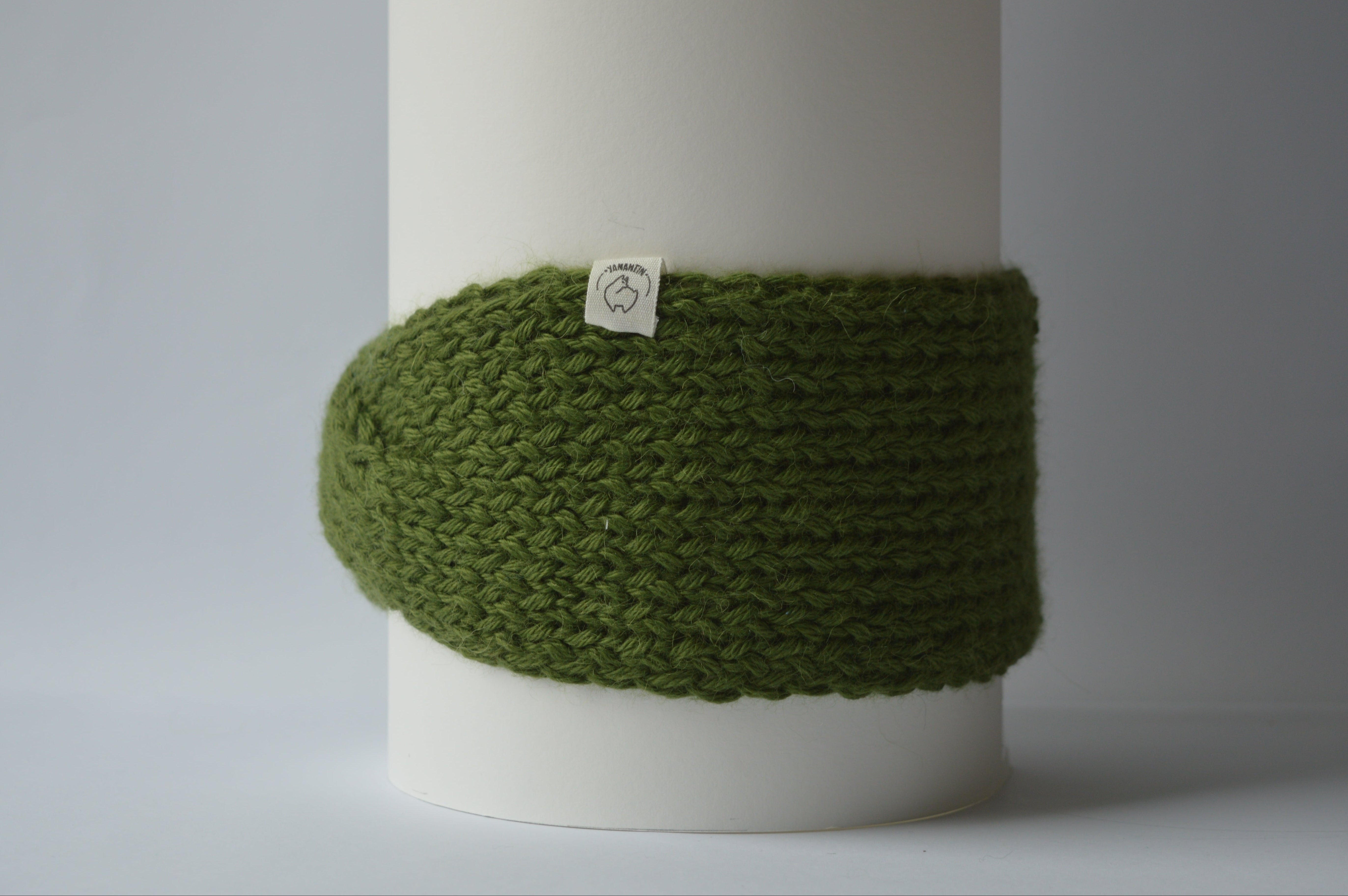 Green knitted headband with an organic cotton label on a gray background