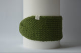 Green knitted headband with an organic cotton label on a gray background
