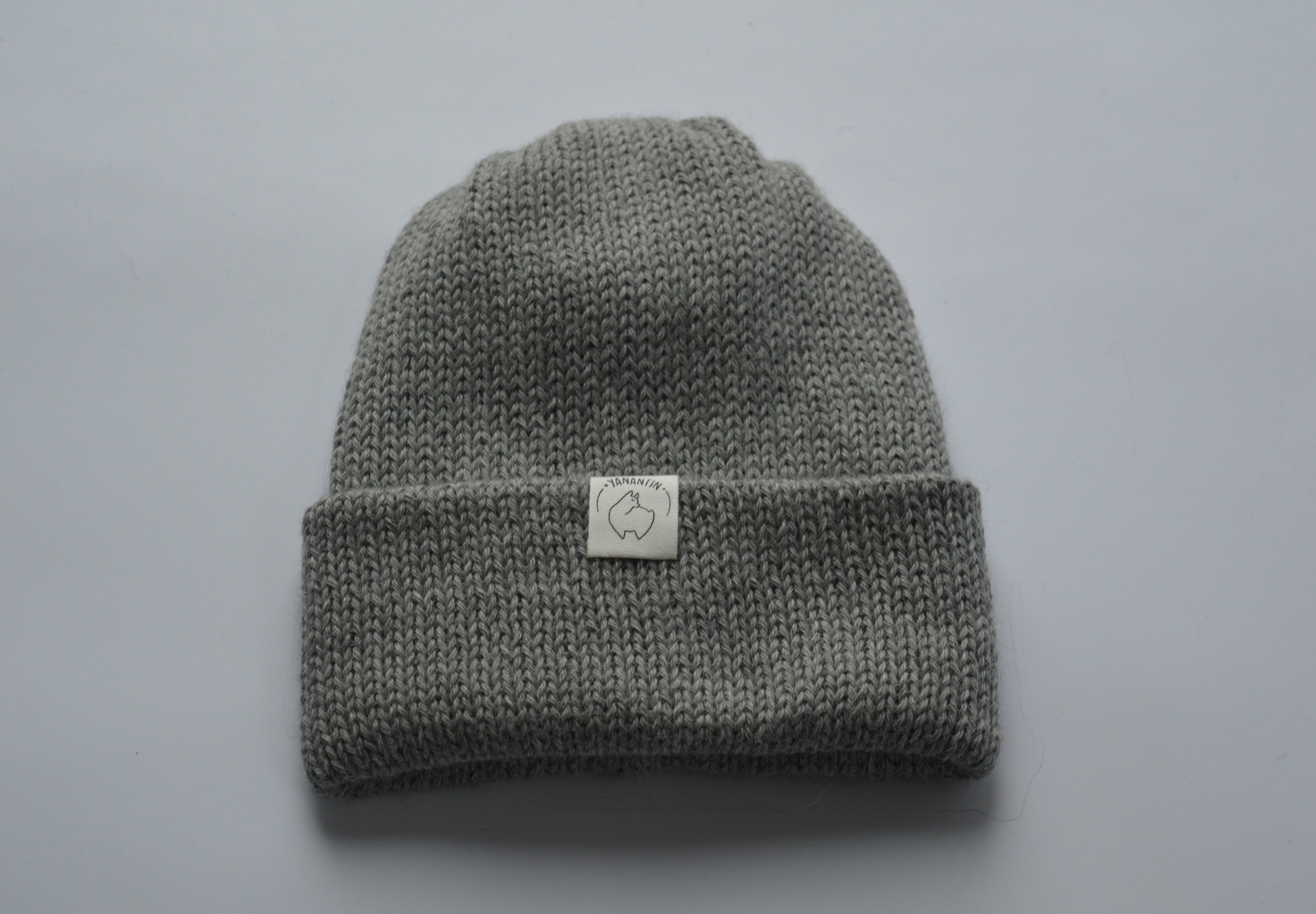 Light Grey knitted baby alpaca hat with a white organic cotton label and folded brim