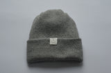 Light Grey knitted baby alpaca hat with a white organic cotton label and folded brim