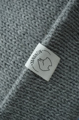 White organic cotton logo of a cute alpaca featuring the brand 'YANANTIN' on a light grey woolen hat