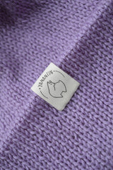White organic cotton logo of a cute alpaca featuring the brand 'YANANTIN' on a purple woolen hat