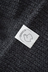 White organic cotton logo of a cute alpaca featuring the brand 'YANANTIN' on a  black woolen hat
