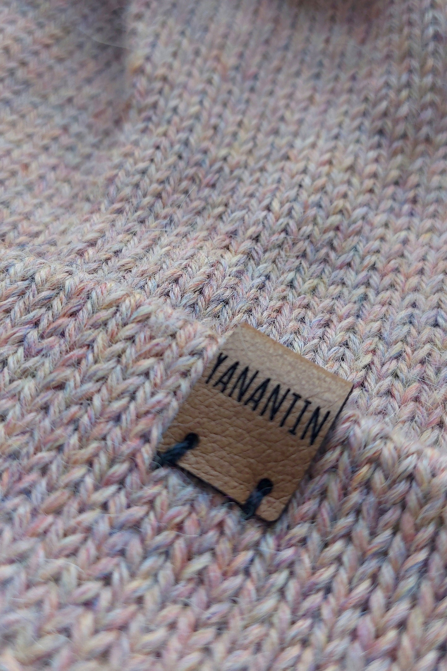 Close-up of the brown vegan leather label on the handmade light pink baby hat.