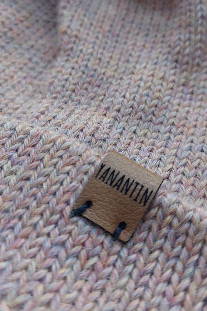 Close-up of the brown vegan leather label on the handmade light pink baby hat.