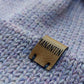 Close-up of the brown vegan leather label on the handmade lila baby hat, highlighting its quality and style.