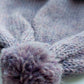 Close-up of the pompom on the handmade lila baby hat, made from soft 100% baby alpaca wool with a foldable edge and brown vegan leather label.