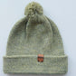 Handmade light green baby hat in soft 100% baby alpaca wool with a pompom, foldable edge, and brown vegan leather label, offering warmth and style.