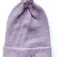 Handmade lila baby hat in soft 100% baby alpaca wool with a pompom, foldable edge, and brown vegan leather label, offering warmth and comfort.
