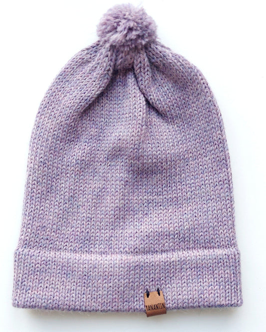 Handmade lila baby hat in soft 100% baby alpaca wool with a pompom, foldable edge, and brown vegan leather label, offering warmth and comfort.
