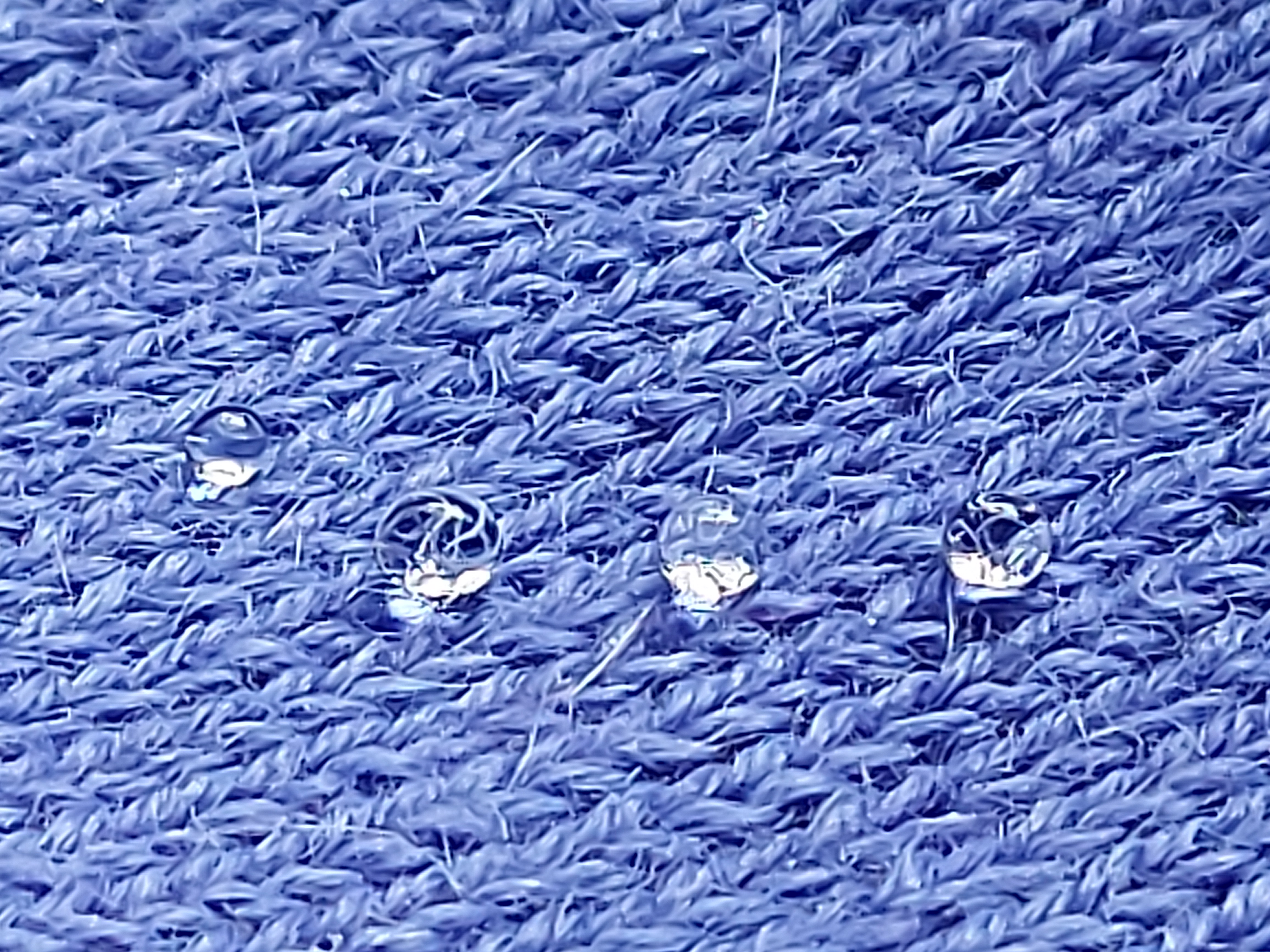 Water drops on top of an alpaca woolen garment. The fabric is water repellent