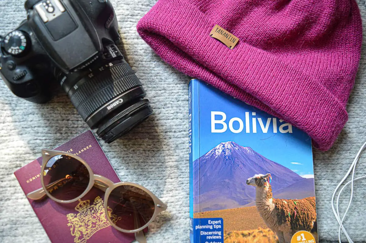 Travel items gather together. Lonely planet travel guide of Bolivia, passport and sunglasses, camera and alpaca woolen hat.