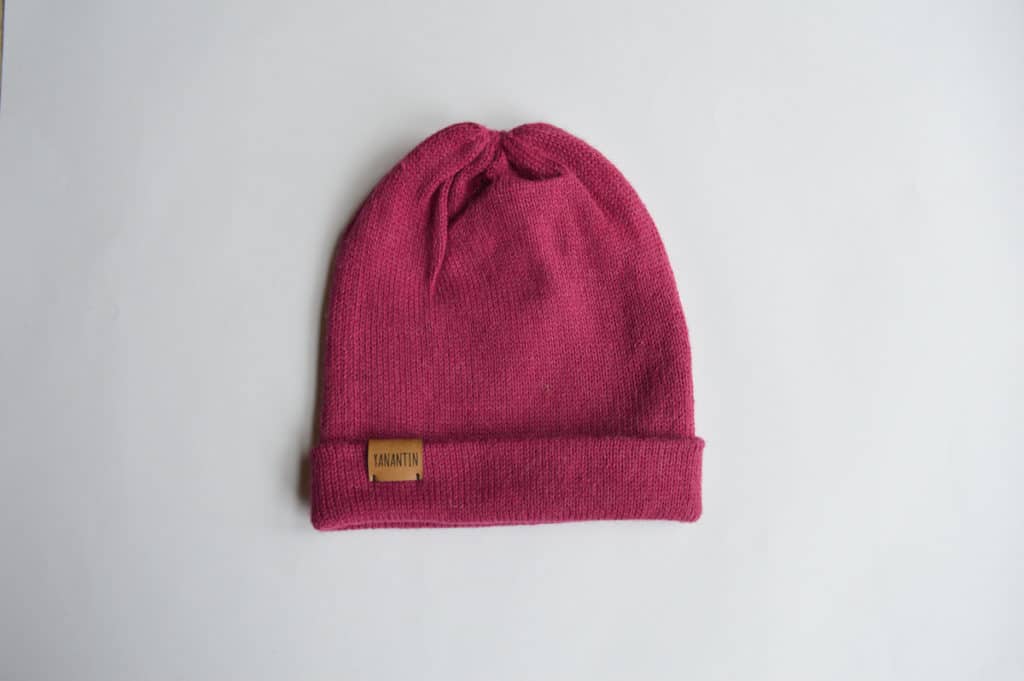 Knitted hat made of 100% alpaca wool. Foldable at the end and with a brown label. Bright pink color.